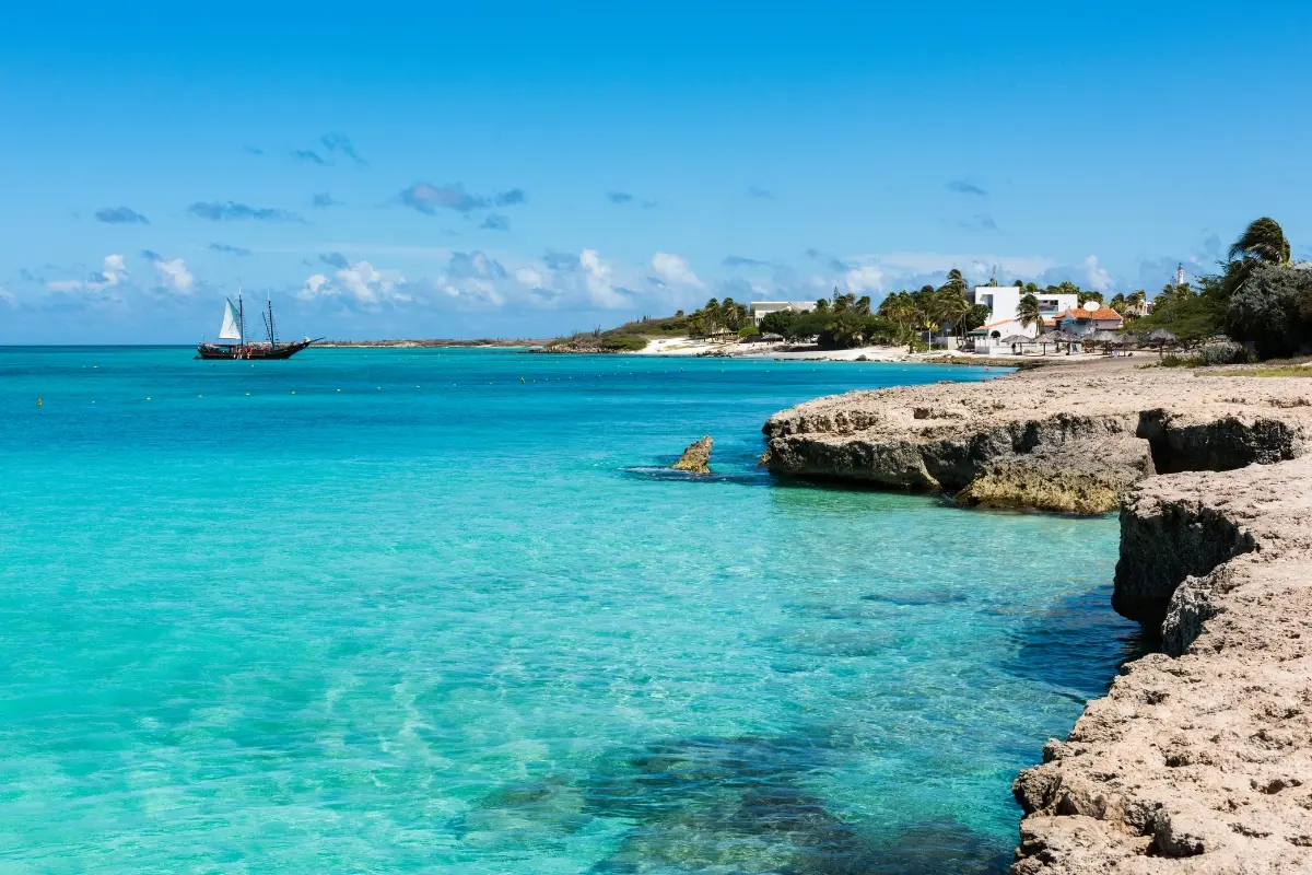 Costa rocosa de Arashi con aguas cristalinas y velero en Aruba