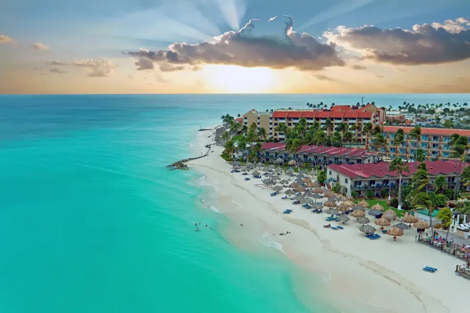 Vista aérea de resorts frente al mar turquesa al atardecer en Aruba